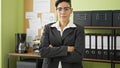 Young beautiful hispanic woman business worker standing with arms crossed gesture and serious face at office Royalty Free Stock Photo