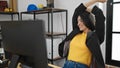 Young beautiful hispanic woman business worker using computer stretching arms at office Royalty Free Stock Photo