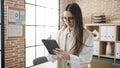 Young beautiful hispanic woman business worker using touchpad with doubt expression at office Royalty Free Stock Photo