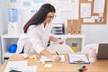 Young beautiful hispanic woman business worker writing on notebook holding paperwork at office Royalty Free Stock Photo