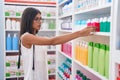 Young beautiful hispanic woman client holding toothpaste at pharmacy Royalty Free Stock Photo