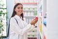 Young beautiful hispanic woman client holding toothpaste at pharmacy Royalty Free Stock Photo