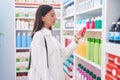 Young beautiful hispanic woman client holding toothpaste at pharmacy Royalty Free Stock Photo