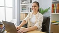 Young, beautiful hispanic woman confidently working her business magic on a laptop, exuding joy and success in a professional