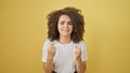 Young beautiful hispanic woman crossing fingers for lucky over isolated yellow background