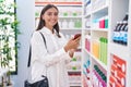 Young beautiful hispanic woman customer smiling confident using smartphone at pharmacy Royalty Free Stock Photo