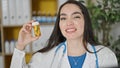 Young beautiful hispanic woman doctor holding bottle of pills at the clinic Royalty Free Stock Photo