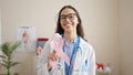 Young beautiful hispanic woman doctor holding breast cancer awareness pink ribbon at clinic Royalty Free Stock Photo