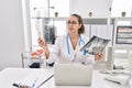 Young beautiful hispanic woman doctor looking xray sitting on table at clinic Royalty Free Stock Photo