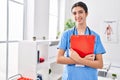 Young beautiful hispanic woman doctor smiling confident holding clipboard at clinic Royalty Free Stock Photo