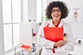 Young beautiful hispanic woman doctor smiling confident holding clipboard at clinic Royalty Free Stock Photo