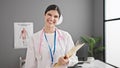 Young beautiful hispanic woman doctor smiling confident holding clipboard at clinic Royalty Free Stock Photo