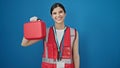 Young beautiful hispanic woman doctor smiling confident holding first aid kit box over isolated blue background Royalty Free Stock Photo
