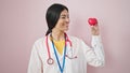 Young beautiful hispanic woman doctor smiling confident holding heart over isolated pink background Royalty Free Stock Photo