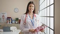 Young beautiful hispanic woman doctor smiling confident holding medical report at clinic Royalty Free Stock Photo