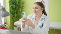 Young beautiful hispanic woman doctor smiling confident using smartphone working at clinic Royalty Free Stock Photo