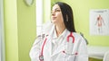 Young beautiful hispanic woman doctor standing with worry expression wearing medical mask at clinic Royalty Free Stock Photo