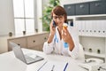 Young beautiful hispanic woman doctor talking on smartphone holding pills bottle at clinic Royalty Free Stock Photo