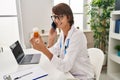 Young beautiful hispanic woman doctor talking on smartphone holding pills bottle at clinic Royalty Free Stock Photo