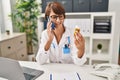 Young beautiful hispanic woman doctor talking on smartphone holding pills bottle at clinic Royalty Free Stock Photo