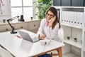 Young beautiful hispanic woman doctor using laptop talking on telephone at clinic Royalty Free Stock Photo