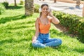 Young beautiful hispanic woman doing yoga exercise using headphones at park Royalty Free Stock Photo