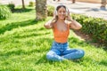 Young beautiful hispanic woman doing yoga exercise using headphones at park Royalty Free Stock Photo