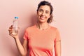 Young beautiful hispanic woman drinking bottle of water looking positive and happy standing and smiling with a confident smile Royalty Free Stock Photo