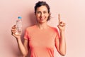 Young beautiful hispanic woman drinking bottle of water smiling with an idea or question pointing finger with happy face, number Royalty Free Stock Photo
