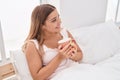 Young beautiful hispanic woman drinking cup of coffee sitting on bed at bedroom Royalty Free Stock Photo