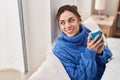 Young beautiful hispanic woman drinking cup of coffee sitting on bed at bedroom Royalty Free Stock Photo