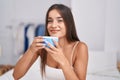 Young beautiful hispanic woman drinking cup of coffee sitting on bed at bedroom Royalty Free Stock Photo