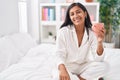 Young beautiful hispanic woman drinking cup of coffee sitting on bed at bedroom Royalty Free Stock Photo