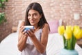 Young beautiful hispanic woman drinking cup of coffee sitting on bed at bedroom Royalty Free Stock Photo