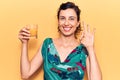 Young beautiful hispanic woman drinking glass of orange juice doing ok sign with fingers, smiling friendly gesturing excellent Royalty Free Stock Photo