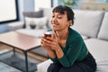 Young beautiful hispanic woman drinking tea sitting on sofa at home Royalty Free Stock Photo