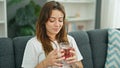 Young beautiful hispanic woman drinking tea sitting on sofa at home Royalty Free Stock Photo