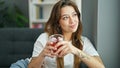 Young beautiful hispanic woman drinking tea sitting on sofa at home Royalty Free Stock Photo