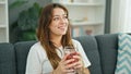 Young beautiful hispanic woman drinking tea sitting on sofa at home Royalty Free Stock Photo