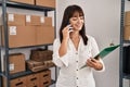 Young beautiful hispanic woman ecommerce business worker holding clipboard talking on smartphone at office Royalty Free Stock Photo