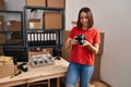 Young beautiful hispanic woman ecommerce business worker smiling confident holding professional camera at office Royalty Free Stock Photo