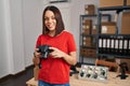 Young beautiful hispanic woman ecommerce business worker smiling confident holding professional camera at office Royalty Free Stock Photo