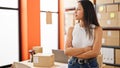 Young beautiful hispanic woman ecommerce business worker standing with arms crossed gesture looking throw the window at office Royalty Free Stock Photo