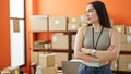 Young beautiful hispanic woman ecommerce business worker standing with arms crossed gesture looking to the side at office Royalty Free Stock Photo