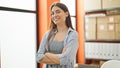 Young beautiful hispanic woman ecommerce business worker standing with arms crossed gesture at office Royalty Free Stock Photo