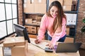 Young beautiful hispanic woman ecommerce business worker using laptop and calculator writing on notebook at office Royalty Free Stock Photo