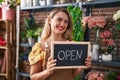 Young beautiful hispanic woman florist smiling confident holding open blackboard at flower shop