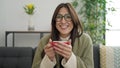 Young beautiful hispanic woman with foam coffee on lips at home