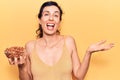 Young beautiful hispanic woman holding bowl with almonds celebrating achievement with happy smile and winner expression with Royalty Free Stock Photo