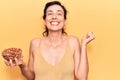 Young beautiful hispanic woman holding bowl with almonds screaming proud, celebrating victory and success very excited with raised Royalty Free Stock Photo